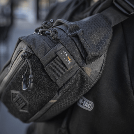 M‑Tac bältesväska Elite Hex visas på en person, tillverkad i Cordura med YKK-dragkedjor, idealisk för dagligt eller taktiskt bruk.