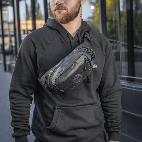 Man bär M‑Tac bältesväska Elite Hex i stadsmiljö, modeinriktad och funktionell med Cordura och YKK-dragkedjor, perfekt för vardagligt bruk.