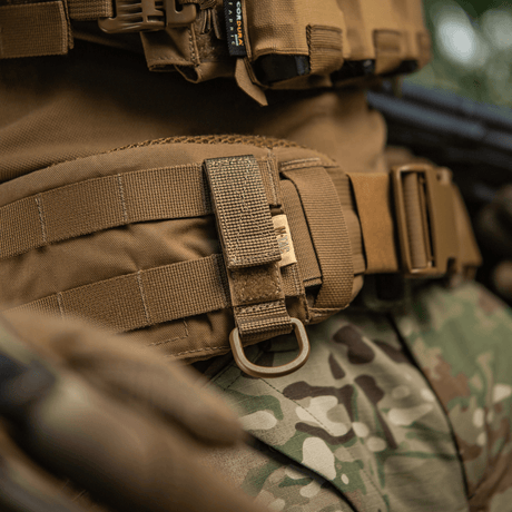 M-Tac fäste med D-ring för MOLLE-system på taktisk utrustning, visar säker upphängning och justerbar Velcro-stängning.