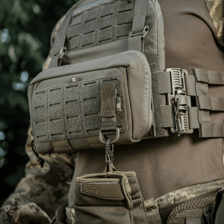 M-Tac fäste med D-ring monterat på taktisk väst med MOLLE-system och Velcro-låsning.