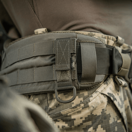 M-Tac fäste med D-ring monterat på taktisk utrustning med MOLLE-system och Velcro.