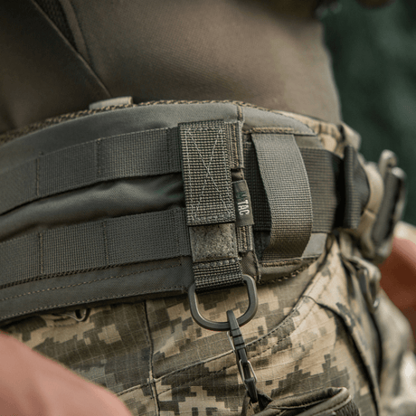 M-Tac fäste med D-ring på taktiskt bälte med MOLLE-system och Velcro för säker upphängning och justerbar passform, idealisk för utomhusbruk.