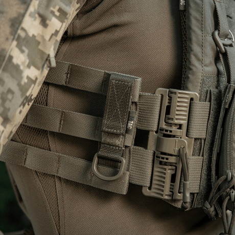 M-Tac fäste med D-ring fastsatt på MOLLE-utrustning med Velcro, idealisk för taktisk användning med säker upphängning och justerbar passform.