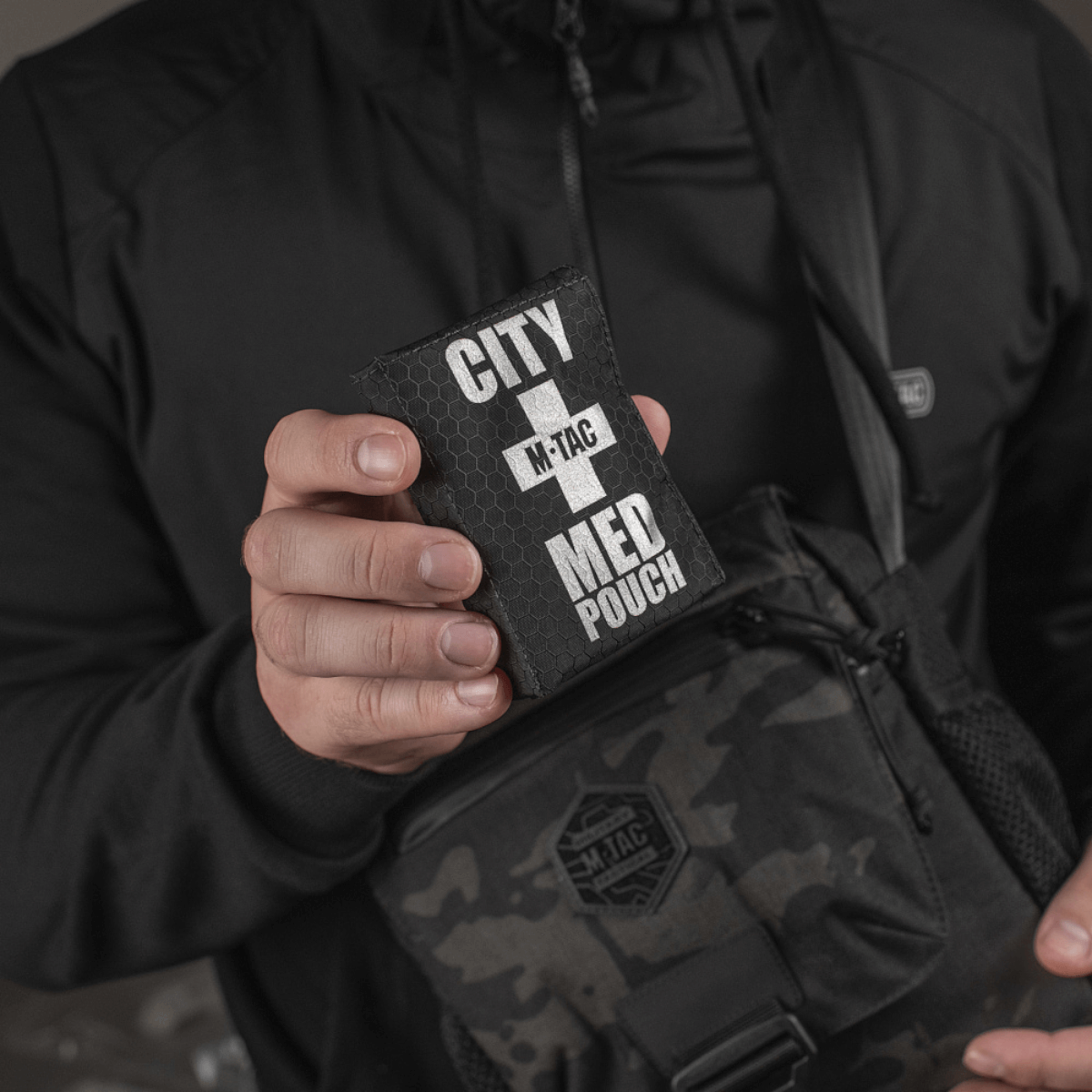 Person holder M-Tac City Med Pouch Hex fremstillet af Hex Polyester, kompakt førstehjælpskit med medicinsk kors og M-Tac-logo.