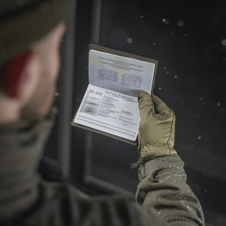 Person håller ett pass skyddat av M‑Tac passfodral i vinterkläder.
