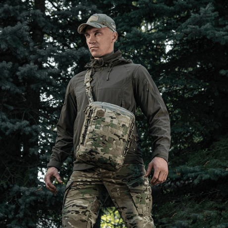 Mand bærer M-Tac Tablet Bag Laser Cut Hex i skovmiljø, camouflagetilbehør med laserudskåret MOLLE til EDC, dokumenter og våben.