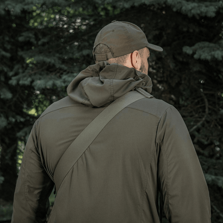 Mand i skov med M-Tac Tablet Bag Laser Cut Hex over skulderen, iført armygrøn jakke og kasket.