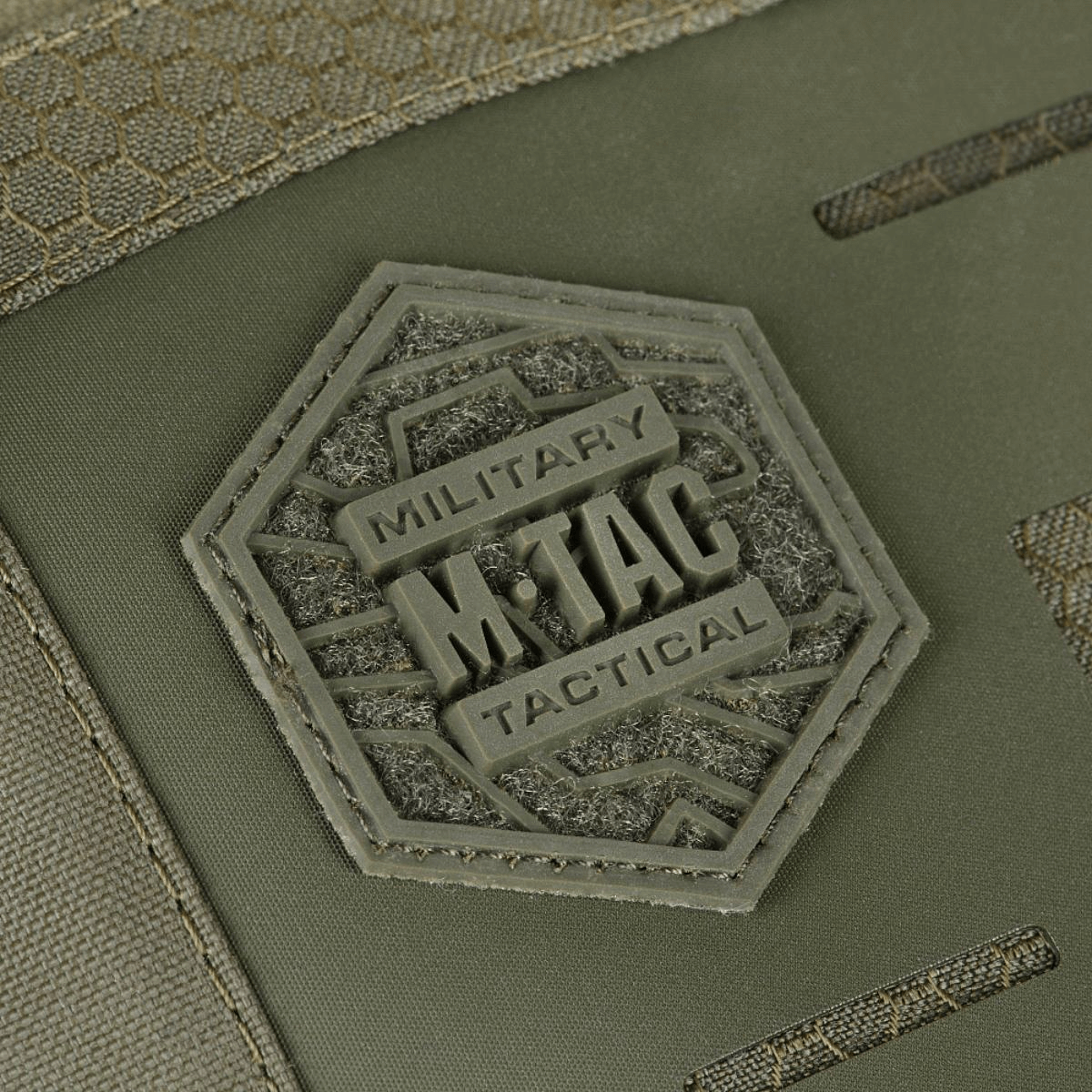 Nærbillede af M-Tac Tablet Bag Laser Cut Hex logo i en sekskant på frontpanelet, lavet af Cordura Hex materiale i olivengrøn.