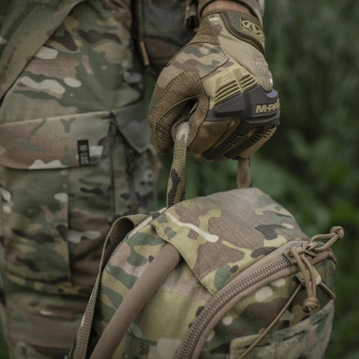 M-Tac STURM Elite Rygsæk i camouflage mønster med MOLLE system, holdt af person i army tøj og taktiske handsker, 15 liter kapacitet.