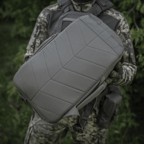 M-Tac STURM Elite Rygsæk i taktisk design med 15 liters kapacitet og slidstærkt Cordura-materiale, holdt af person i camouflageuniform.