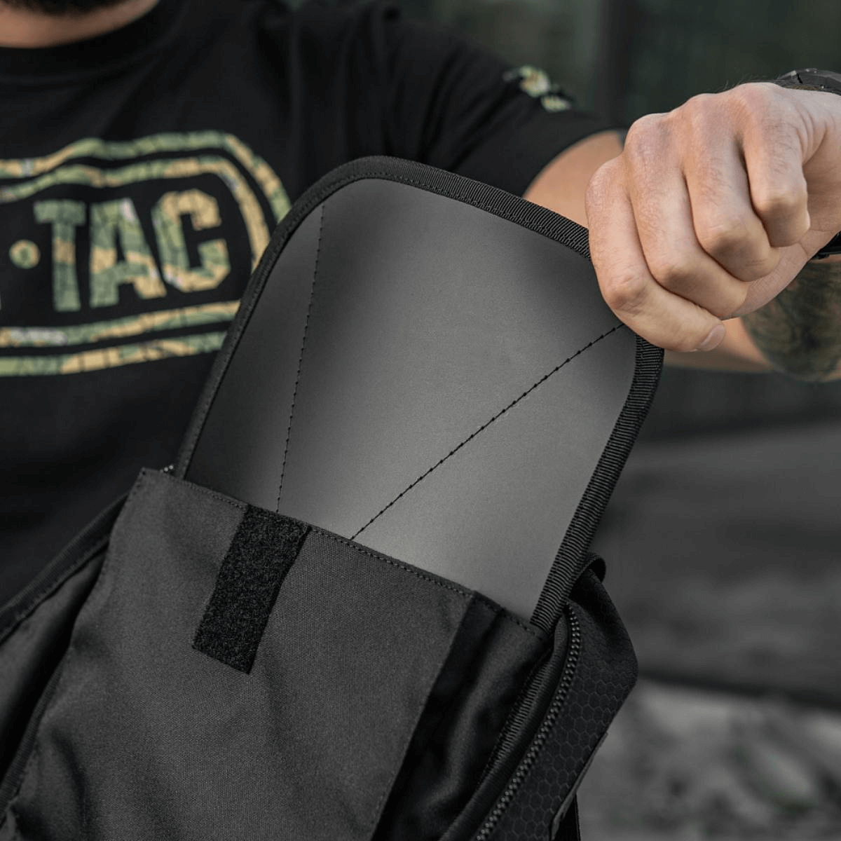 Person indsætter skudsikker plade i taktisk taske, sikkerhedsforbedring