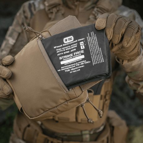 Soldat med M-Tac Large Elite Gen.II Skuldertaske i Cordura 500D materiale og ballistisk panel til taktisk brug og opbevaring af udstyr.