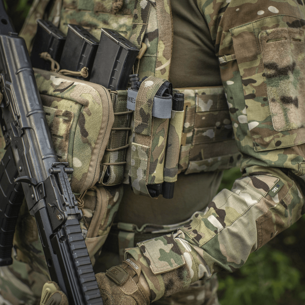 Soldat med M‑Tac Tourniquet Pouch Elastic Gen.5 fastgjort til taktisk vest med camouflagemønster.