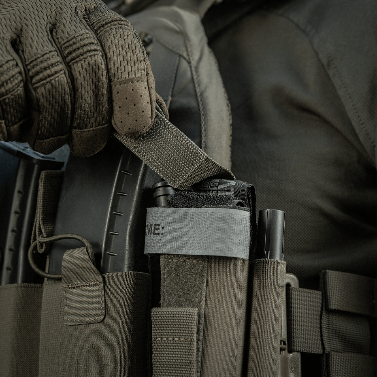 M‑Tac Tourniquet Pouch Elastic Gen.5 fastgjort til taktisk udstyr med elastisk bånd og velcro, viser hurtig adgang og sikker opbevaring.