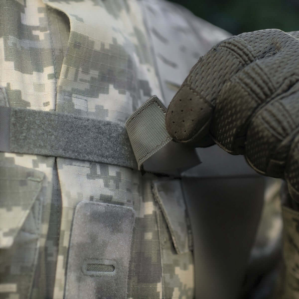 Nærbillede af en hånd i handske, der justerer M-Tac Skulderstropper til taktisk bælte Laser Cut på camouflagetøj.