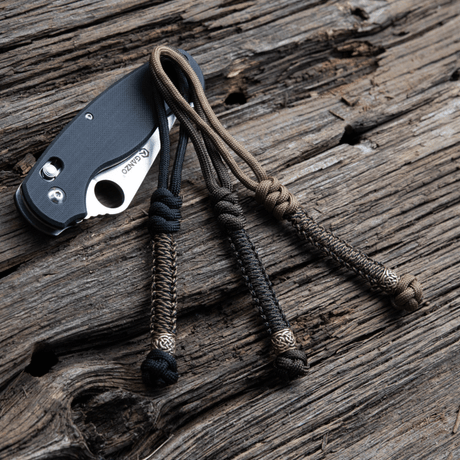 M‑Tac Knife Lanyard Scandinavian stilfullt flätad paracord för fickknivar på träyta.