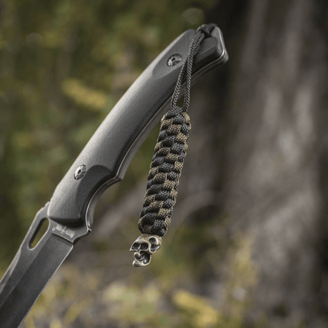 M-Tac Knife Lanyard Helix Skull på en kniv, flätad paracord tillför stil och funktion med karaktäristisk skalledesign.