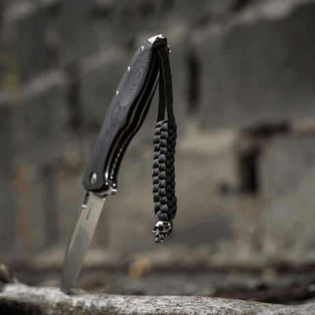 Svart M-Tac Knife Lanyard Cuboid Skull paracord med dekorativ Cuboid Skull-pärla, flätad för kniv för unikt uttryck och praktisk användning.