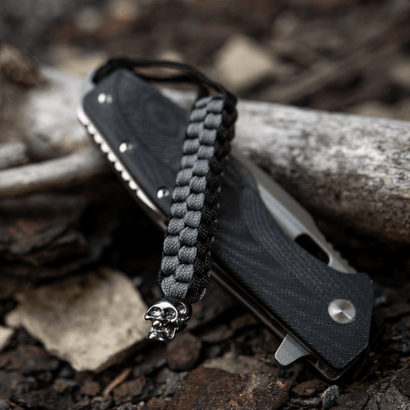 M-Tac Knife Lanyard Cuboid Skull med rå paracord-design och dekorativ skallepärla, praktisk för att förlänga greppet vid knivhantering.