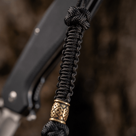 M-Tac Knife Lanyard Celtic i svart flätad paracord med dekorativ detalj, tillför stil till kniven och gör den lättare att hitta.