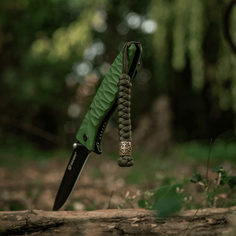 M-Tac Viper Lanyard Scandinavian i flätad paracord med Viper-pärla vid en fickkniv i naturen. Stilfullt tillbehör.