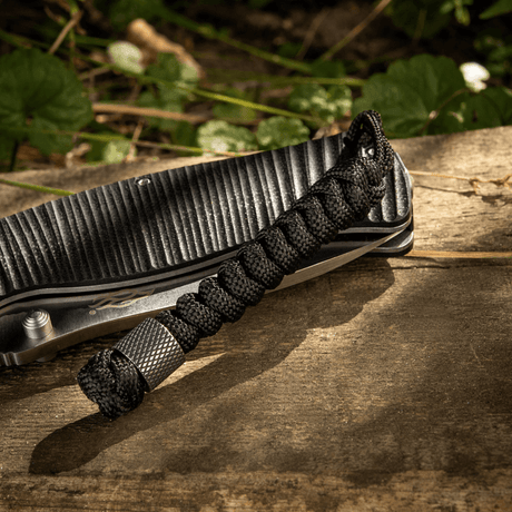 M-Tac Viper Lanyard Stainless Steel med flätad paracord och Viper-pärla, stiligt knivtillbehör, svart lanyard på träbakgrund.