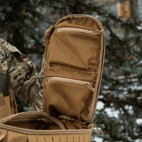 M-Tac Rygsäck Sturm Elite Gen.II med öppnat kuffertstilfack och två nätfickor för EDC-utrustning utomhus i skogsmiljö.