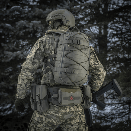 Taktisk person med M-Tac Ryggsäck Sturm Elite Gen.II i skogsmiljö bärande kamouflageuniform, sedd bakifrån