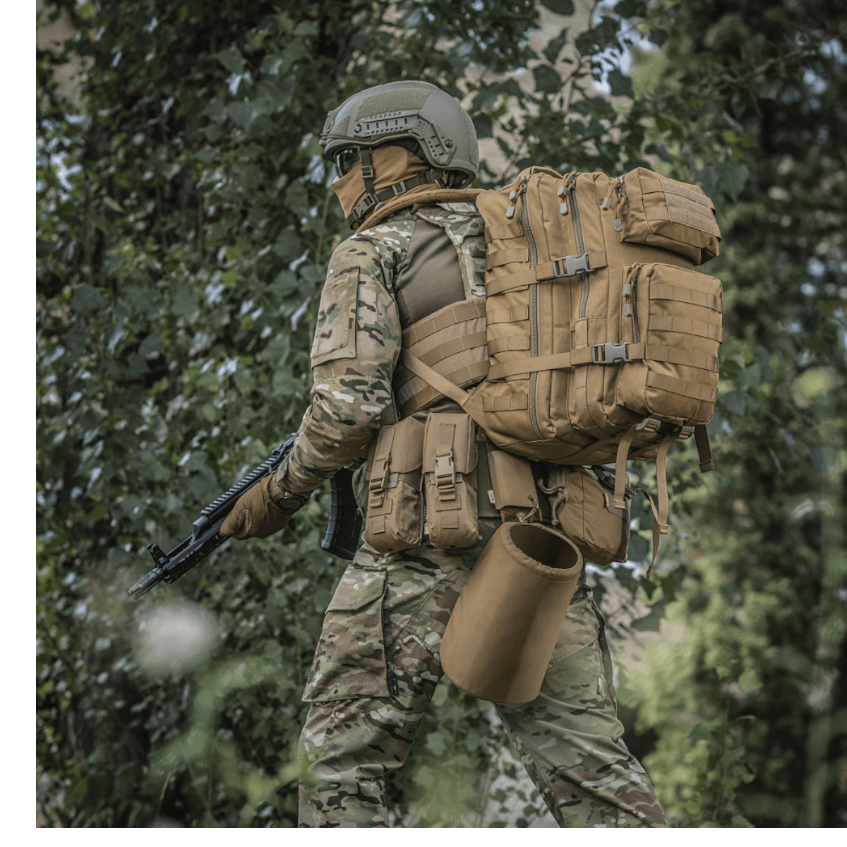 Soldat iført M-Tac Large Assault Pack Rygsæk i skovmiljø, klar til vandretur med MOLLE-system og justerbare skulderremme.