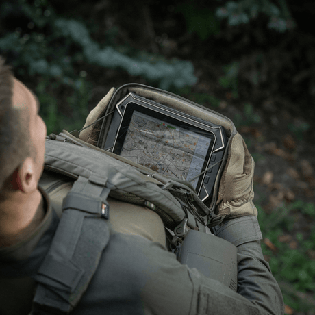 Person med M-Tac Admin Pouch Large Elite håller en tablet i en skog.