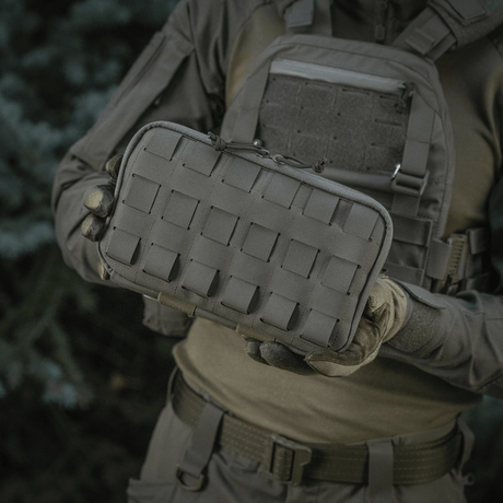 Person håller M-Tac Admin Pouch Large Elite-väska med laserutskuret velcro-panel. Lämplig för förvaring av taktisk utrustning. Tillverkad av Cordura 500D.
