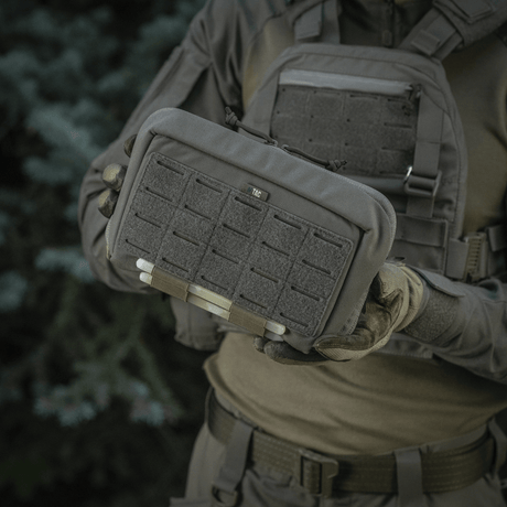 Taktisk M-Tac Admin Pouch Large Elite hålls av person i uniform med velcro-paneler, tillverkad av slitstarkt Cordura 500D.