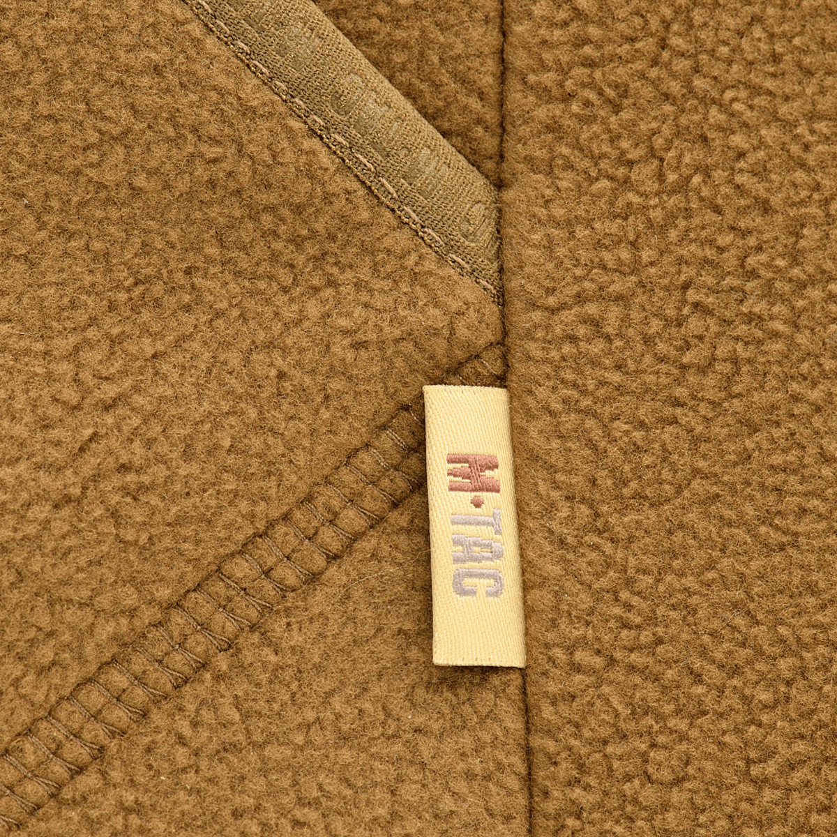 Nærbillede af M-Tac Lite Microfleece Hættetrøje i brun fleece med M-Tac logoetiket. Perfekt til hverdag, træning og friluftsliv.