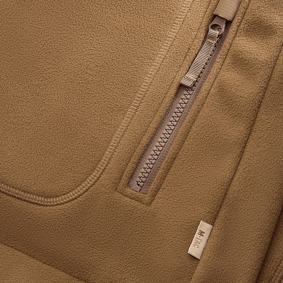 M-Tac Norman Windblock Fleecejakke detaljer med lynlås og label, designet for komfort og varme i koldt vejr. Vind- og kuldebeskyttelse.