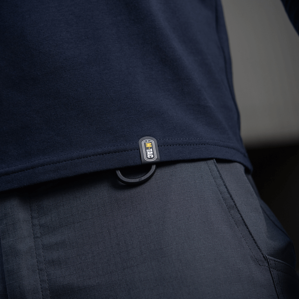 M-Tac Long-sleeve T-shirt 93/7 i mørkeblå med holdbar og elastisk bomuld/elastan blanding, tæt på visning af logoet tæt på taljen.