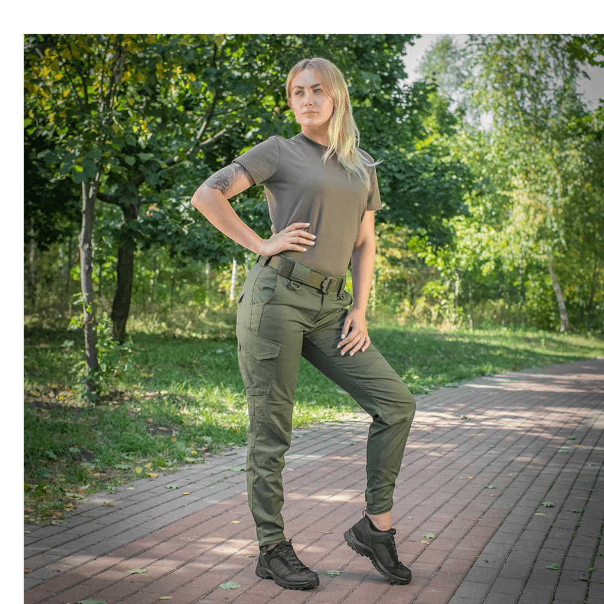 Kvinde iført M-Tac Bukser Aggressor Dame Flex i en have, med fokus på komfort og fleksibilitet, perfekt til træning og hverdagsbrug.