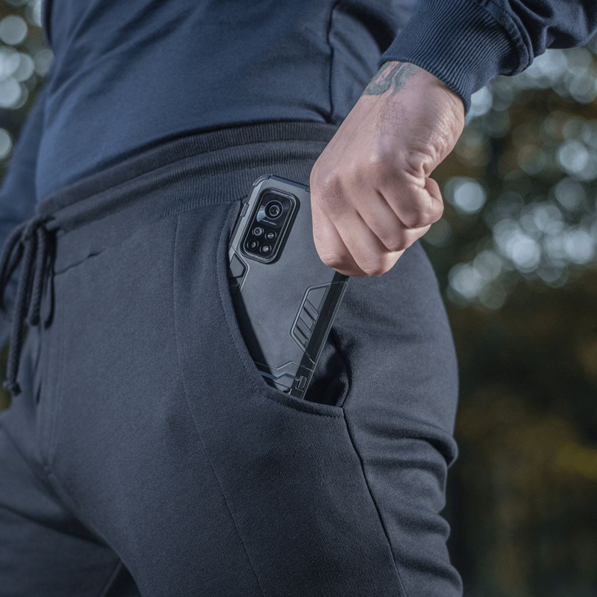 M-Tac Bukser Stealth Cotton med mobiltelefon i sidelomme, fremhæver komfort og funktionalitet, perfekte til sport og hverdag.