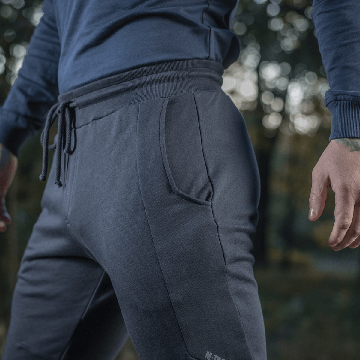 Mand klædt i M-Tac Bukser Stealth Cotton til sport og hverdag, set i nærbillede med fokus på komfort og stilfuldt design.