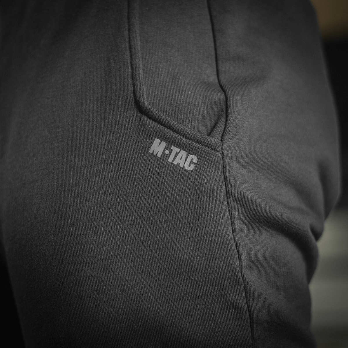 Nærbillede af M-Tac Bukser Cotton Classic med sidelomme og M-Tac logo, fremstillet af 100% bomuld, ideel til sport og daglig brug.
