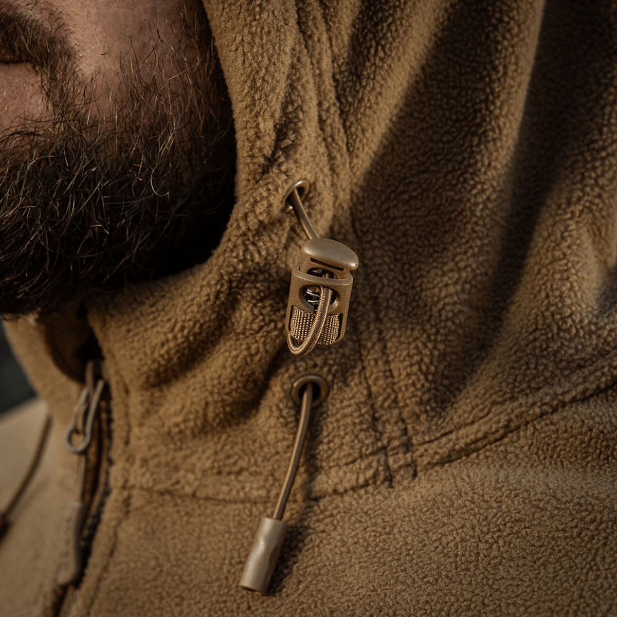 Nærbillede af M-Tac Division Gen.II Windblock Fleecejakke med hætte og snøre, designet til at beskytte mod vind og kulde.