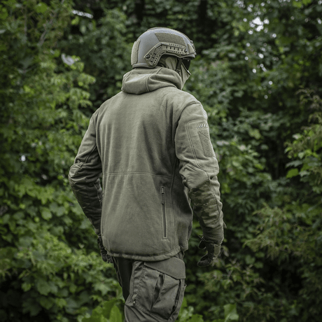 Mand iført M-Tac Division Gen.II Windblock Fleecejakke i skovmiljø, designet til beskyttelse mod vind og kulde i køligt vejr.