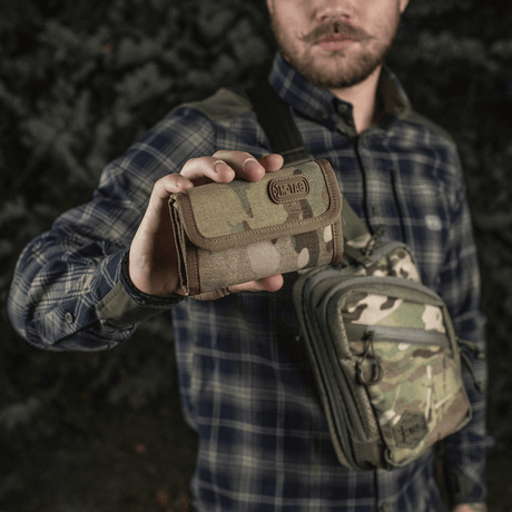 Man håller M-Tac Plånbok Elite Gen.II i kamouflage, tillverkad i slitstarkt Cordura 500D med praktiska fack och YKK-dragkedjor.