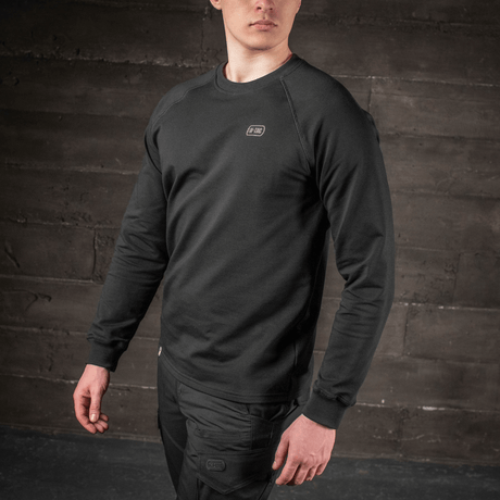 Man bär M-Tac Raglan Athlete sweatshirt med raglanärmar i svart färg, idealisk för sport och vardagsbruk