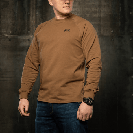 M-Tac Raglan Athlete sweatshirt med rund hals och raglanärm i coyote, perfekt för sport och vardag, sedd i en industriell miljö.
