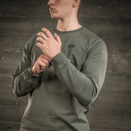 M-Tac Raglan Athlete sweatshirt med raglanärmar i olivfärg, designad för mångsidig användning och maximal rörelsefrihet, sedd på en person.