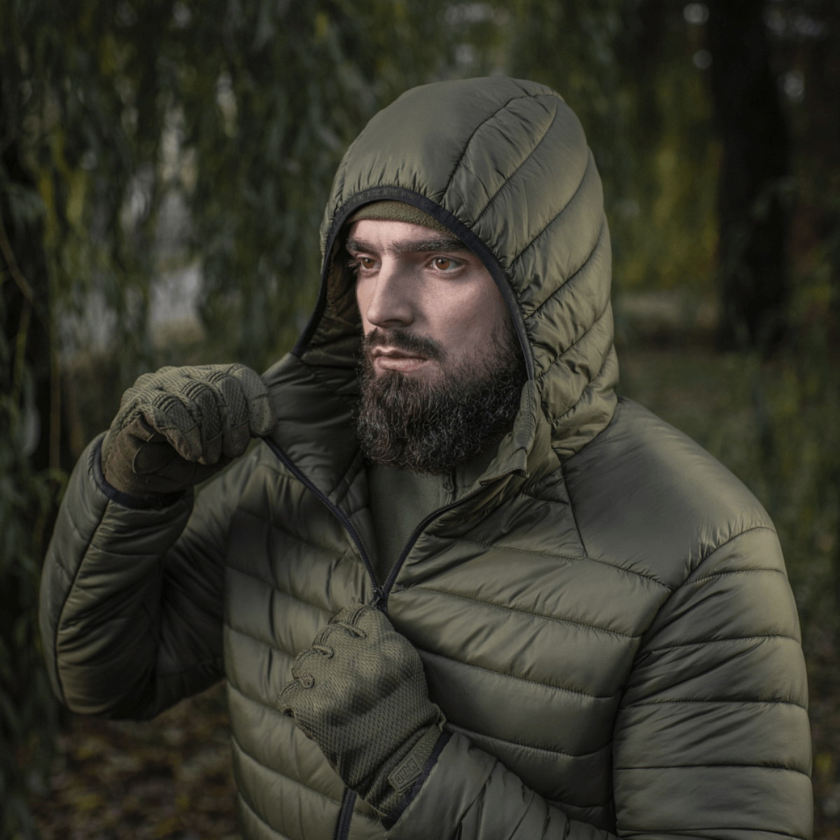 Mand iført M-Tac Stalker Gen.III Jakke i naturen, viser jakke med hætte og lynlås, ideel til kolde sæsoner.