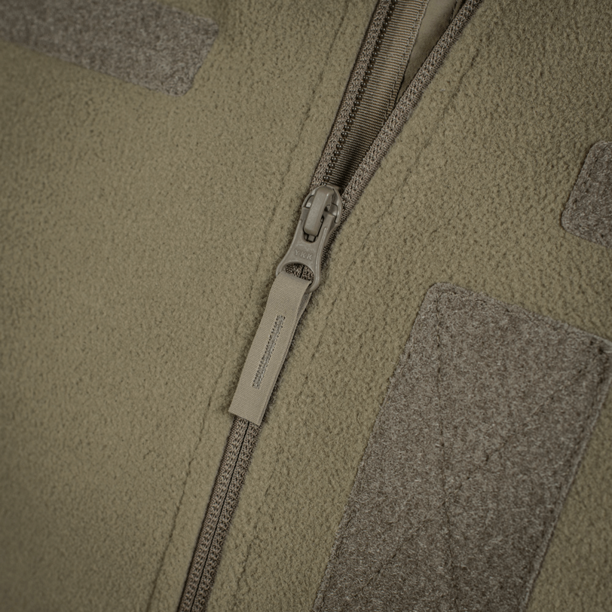 Nærbillede af M-Tac Combat Fleece Polartec Jakke lynlås og stofdetaljer i olivengrøn farve, ideel til taktisk brug.