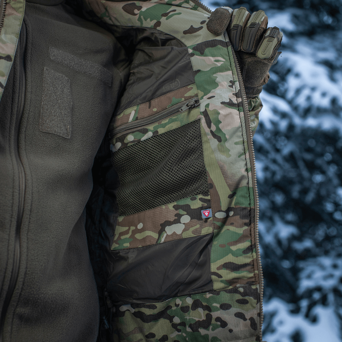Detalje af M-Tac Alpha Gen.IV Pro Primaloft Vinterjakke med original Multicam design i snevejr, viser jakkeindretning og materialer.