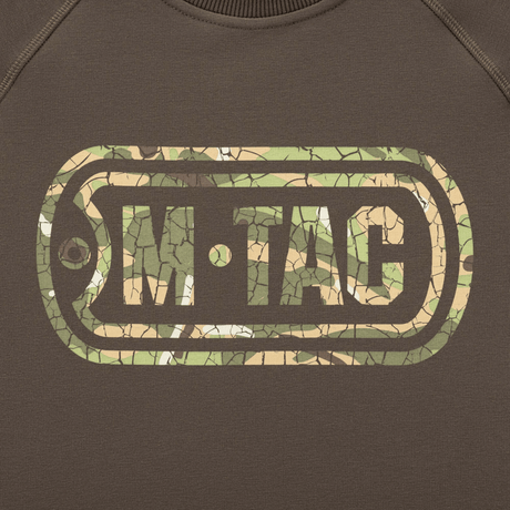 M-Tac Raglan Logo med camouflage print og 'Born by Revolution – Hardened by War' slogan på ærmet, komfort og stil til taktisk brug.