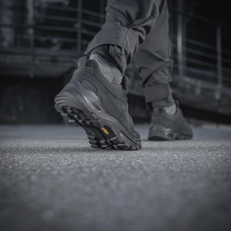 En mand iført M-Tac Tactical Sneakers Patrol R Vent går hen over en betonoverflade og viser skoens slidstærke gummisål.
